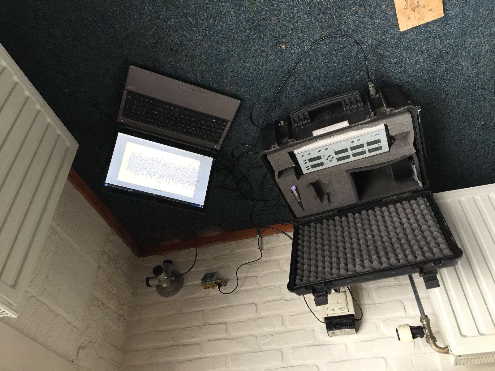 Traditional vibration meter in a case with a laptop, next to an early Frogwatch prototype on the wall
