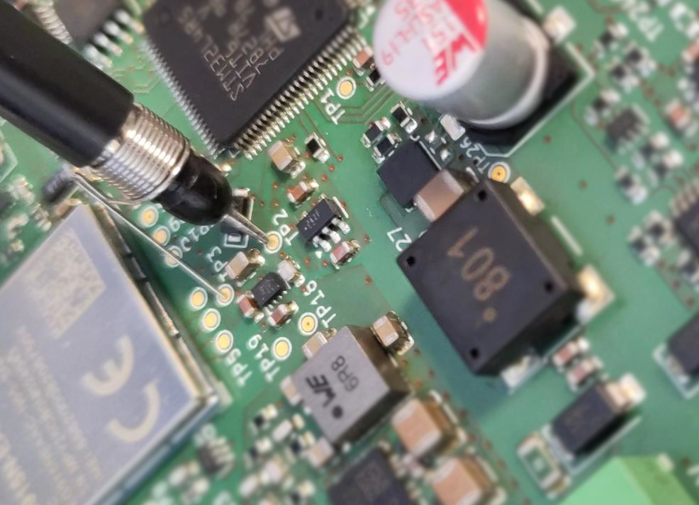 Close-up van testpads op de PCB met een scope-probe aangesloten